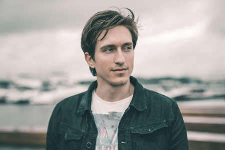 Portrait of a man in a jeans standing on a pier near the yachtの写真素材