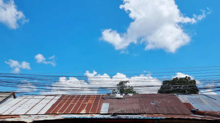 Old house with rusty roof and blue sky with white cloud