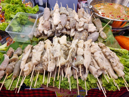 Squid eggs on skewers stacked on top of green vegetables, grilled to perfection and dipped in Thai seafood sauceの写真素材