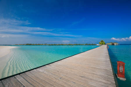 Bridge leading to overwater bungalow in blue lagoon around tropical islandのeditorial素材