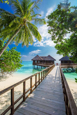 Bridge leading to overwater bungalow in blue lagoon around tropical islandの写真素材
