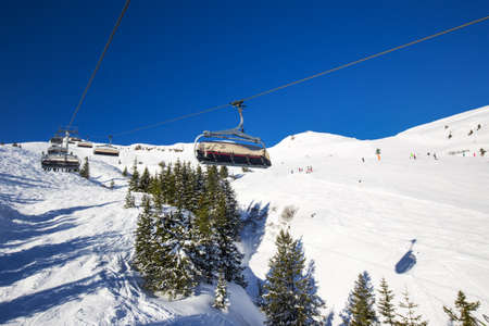 Skiers on ski lift enjoying the view to foggy Alps in Austria and beautiful snowy country panorama in famous Kitzbuehel mountain ski resort, Tyrol, Austriaのeditorial素材