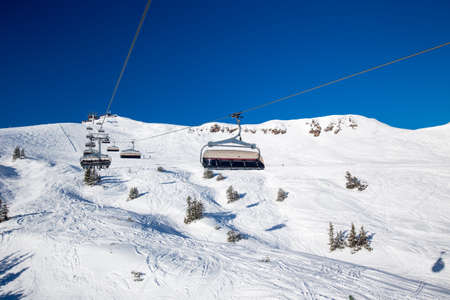 Skiers on ski lift enjoying the view to foggy Alps in Austria and beautiful snowy country panorama in famous Kitzbuehel mountain ski resort, Tyrol, Austriaのeditorial素材