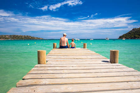 Father and his little son enjoying the view from  sandy Santa Giulia beach with tourquise clear water and pine trees, Corsica, Franceの写真素材