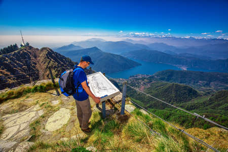 Hiker on  Monte Generoso mountain looking at Lugano city, San Salvatore mountain and Lugano lake, Canton Ticino, Switzerlandの写真素材