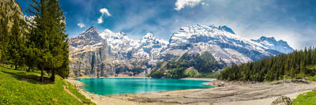 Amazing tourquise Oeschinnensee with waterfalls, wooden chalet and Swiss Alps, Berner Oberland, Switzerland.の写真素材
