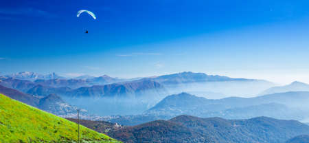 Paraglider over the Lugano city, San Salvatore mountain and Lugano lake seen from Monte Lema, Canton...