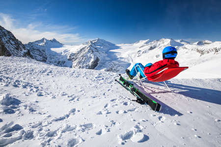 Young happy attractive skier sitting on the top of mountains enjoying the view from Presena Glacier, Tonale, Italy.の写真素材