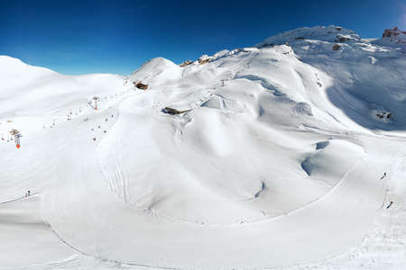 Beautiful winter landscape with Swiss Alps. Skiers skiing in famous Engelgerg - Titlis ski resort,...