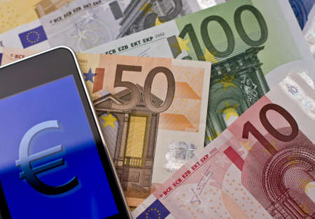 handheld with euro sign on european banknotesの写真素材