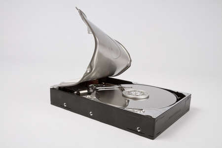 opened hard disk with bended cover in grey backgroundの写真素材