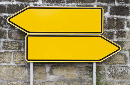 direction signs with wall in background. yellow signs. arrow shapeの写真素材