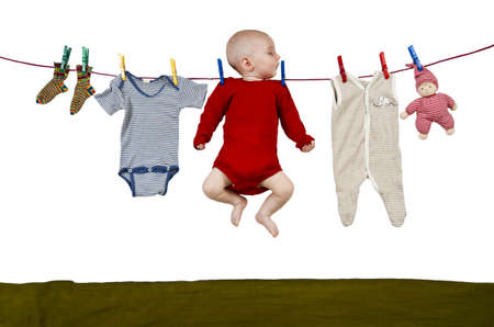 young child hanging at clothes line together with toys and clothingの写真素材