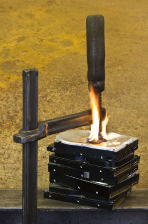 clamp pressing on burning stack of hard drives in rusty backgroundの写真素材