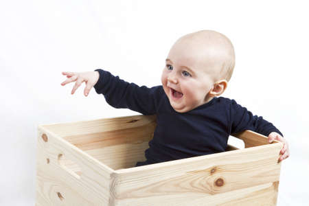 young child sitting in wooden box pointing to the leftの写真素材
