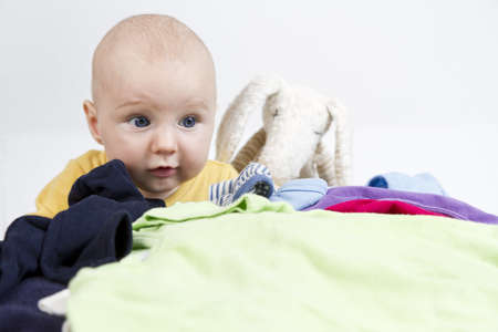 young child looking over many clothesの写真素材