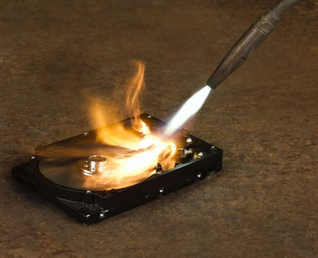 burning a hard disk drive with a welding torch in rusty backgroundの写真素材