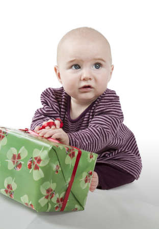 young baby sitting and holding gift looking alienatedの写真素材