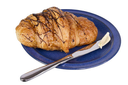 knife and croissant with chocolate on blue dishの写真素材