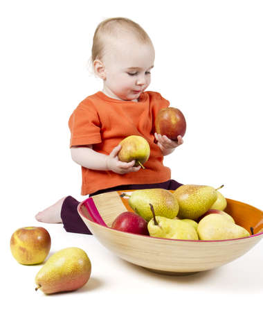 baby with apples and pears laying in bowl - studio shotの写真素材