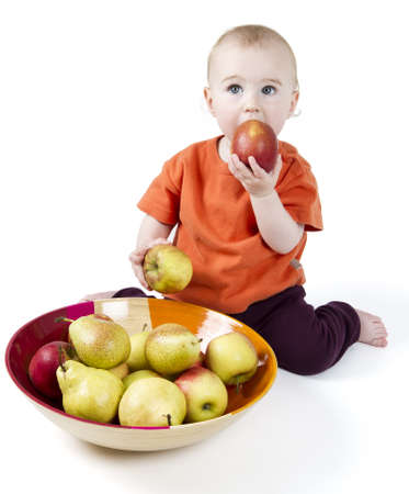 baby with apples and pears laying in bowl - studio shotの写真素材