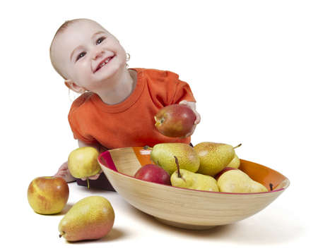 baby with apples and pears laying in bowl - studio shotの写真素材