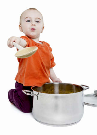 baby with big cooking pot and wooden spoon isolated on white backgroundの写真素材