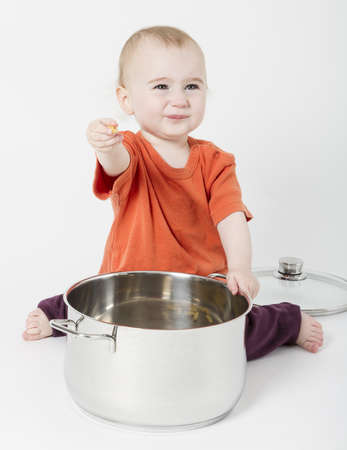 baby with big cooking pot on neutral backgroundの写真素材