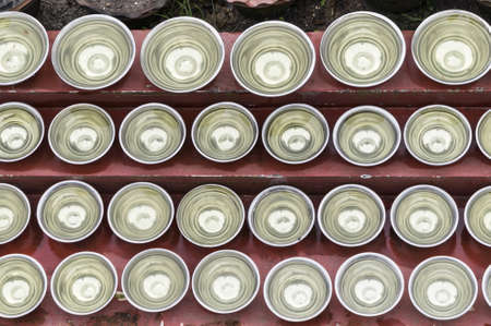 many small bowls with water around a temple in nepalの写真素材