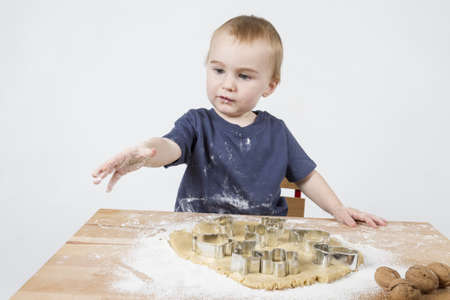 young child making cookies on small wooden deskの写真素材
