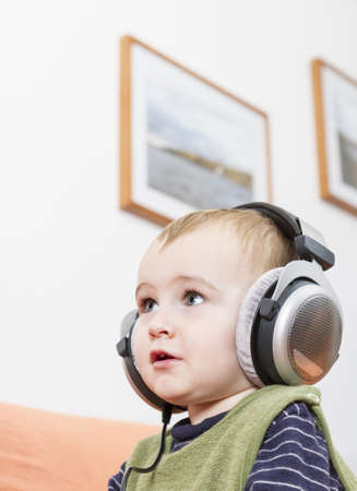 young child on couch with big earphoneの写真素材