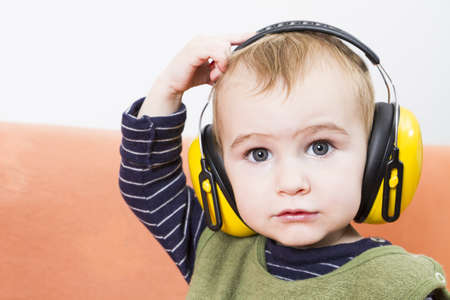 young child on couch with yellow earmuffsの写真素材