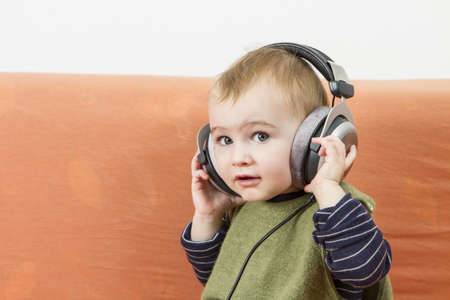 young child on couch with big earphoneの写真素材