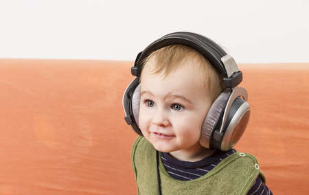 young child on couch with big earphoneの写真素材