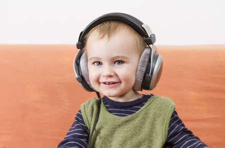 young child on couch with big earphoneの写真素材