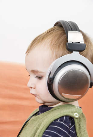 young child on couch with big earphoneの写真素材
