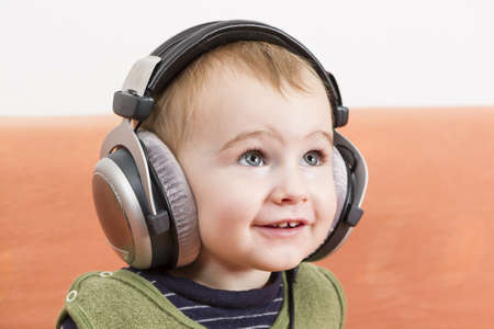 young child on couch with big earphoneの写真素材