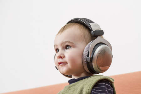 young child on couch with big earphoneの写真素材