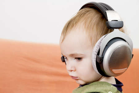 young child on couch with big earphoneの写真素材