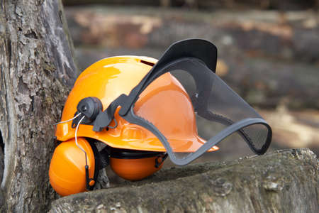 orange protective helmet with ear- and face- protection   Outdoor shot in woody ambianceの写真素材