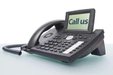 modern business voip phone on glass desk with the words - Call us - in the displayの写真素材