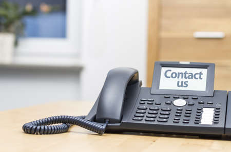 modern voip telephone on wooden desk saying CONTACT USの写真素材
