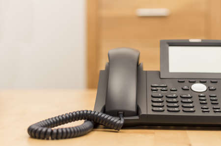 modern black phone on wooden desk with blurred backgroundの写真素材