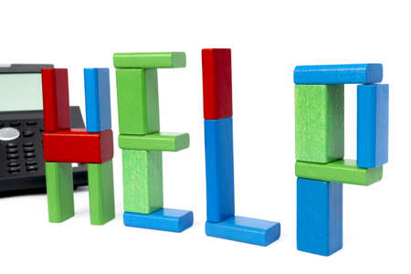 the word help made with toy bricks and a phone in background  isolated on white backgroundの写真素材