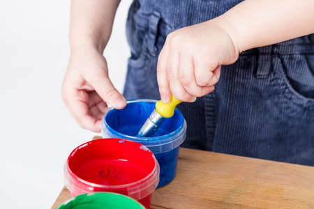 child holding brush in blue paint tubの写真素材