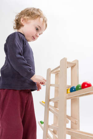young child playing with wooden ball path  studio shot in grey backgroundの写真素材