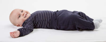 smiling toddler in blue clothing laying down  vertical imageの写真素材