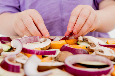 small hands preparing fresh pizza with many vegetablesの写真素材