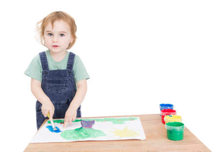 cute girl painting on small desk in grey background  studio shotの写真素材