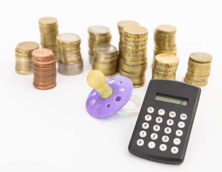 pacifier with hard money and small pocket calculator in light background の写真素材